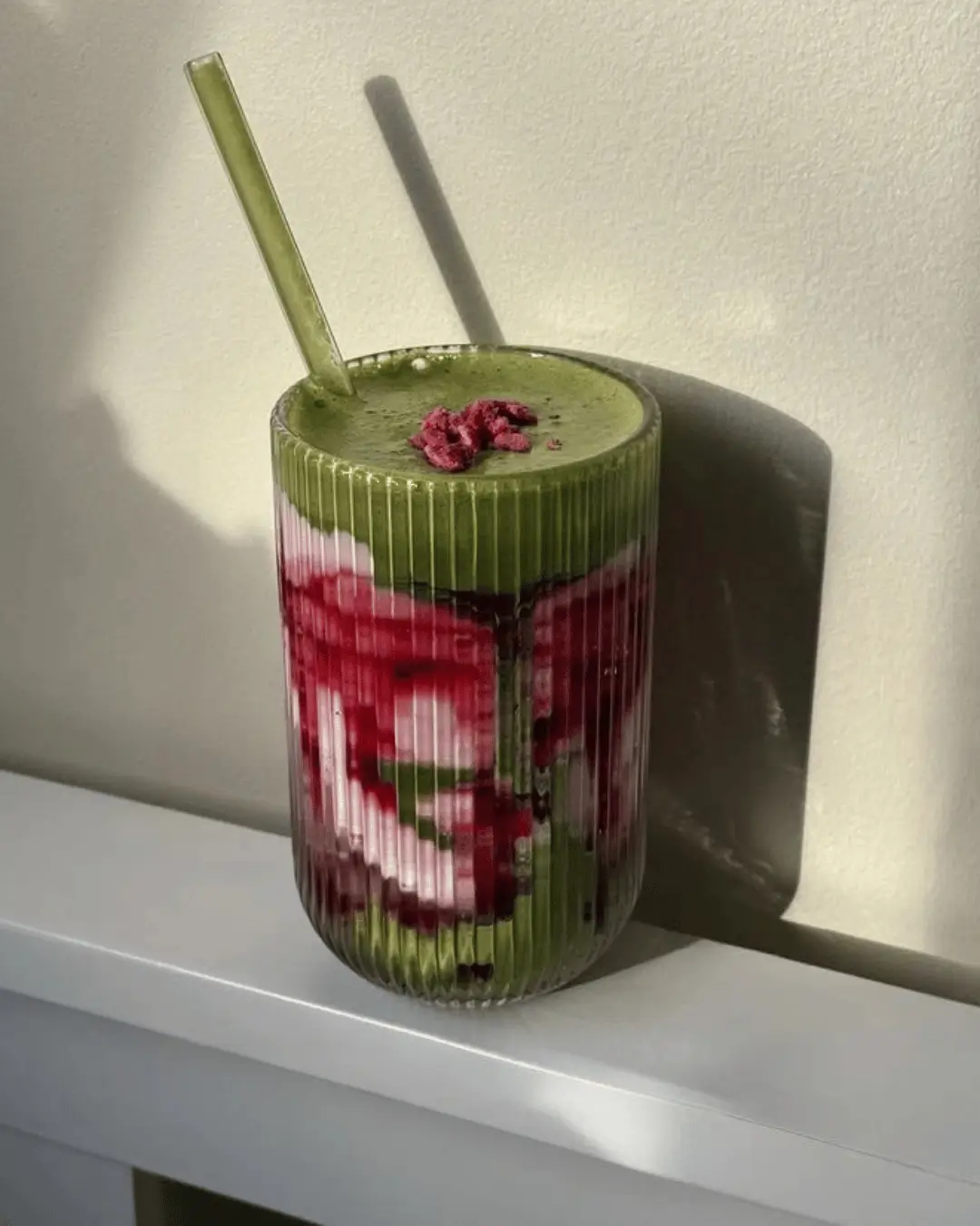 Smoothie detox em camadas verde e vermelha em copo de vidro canelado