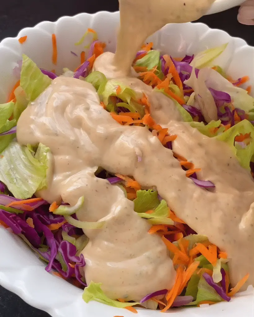 Molho cremoso claro cobrindo salada de repolho roxo e cenoura