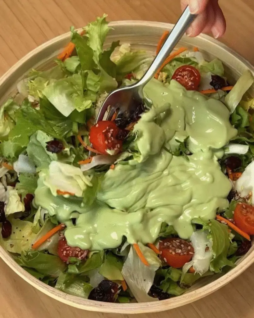 Molho verde de abacate despejado sobre folhas e tomate cereja
